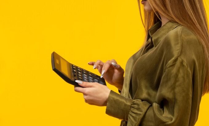 Mulher usando calculadora para entender se a empresa não pagar a rescisão em dez dias e calcular os valores devidos.