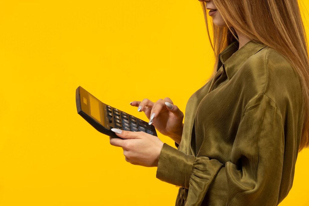 Mulher usando calculadora para entender se a empresa não pagar a rescisão em dez dias e calcular os valores devidos.