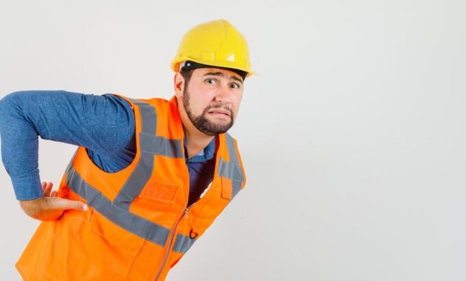 Trabalhador com dor nas costas representando situação relacionada à estabilidade por acidente de trabalho.